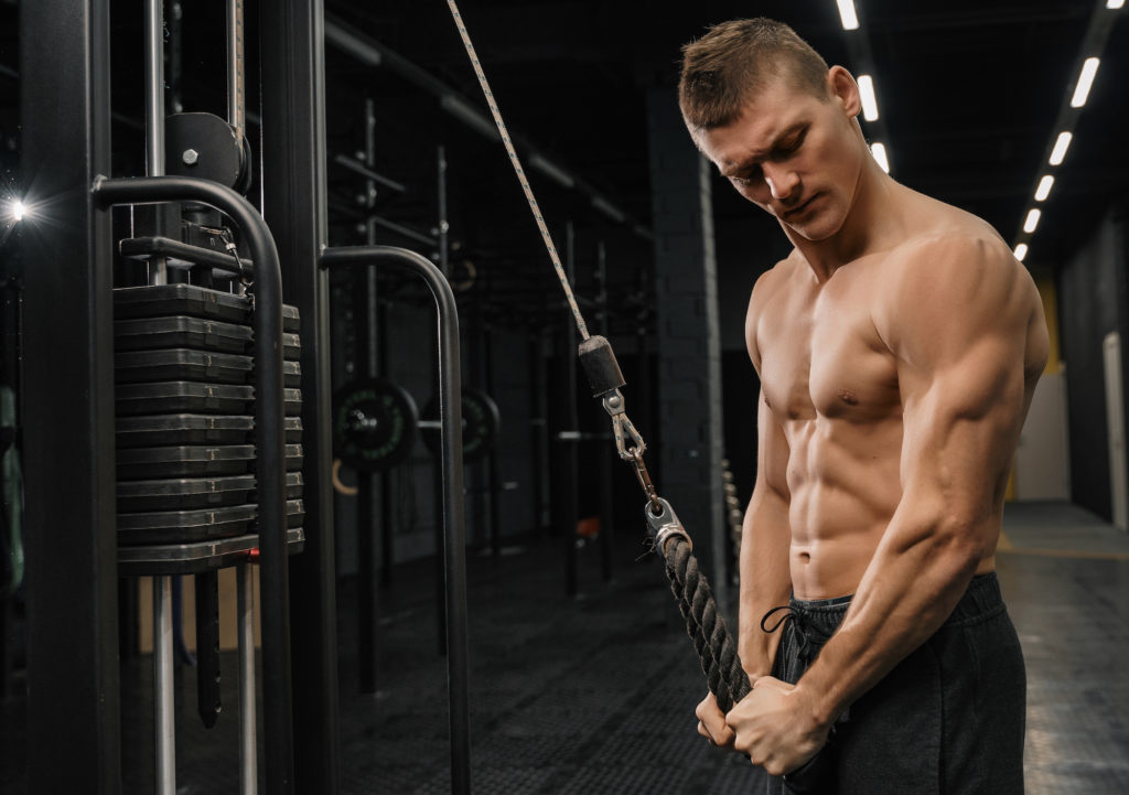 Un beau gaillard s'entraînant aux triceps dans une salle de sport, en train de gonfler son corps, en train de faire du bodybuilding.